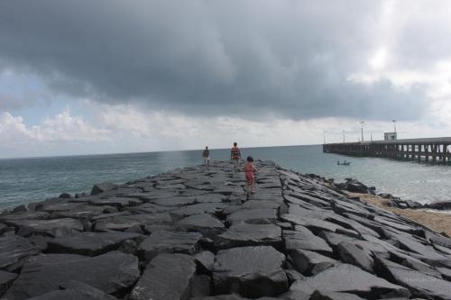 a group of people standing on a pier near the water at Micasa Hostels in Puducherry