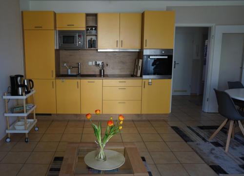 a kitchen with yellow cabinets and a vase of flowers on a table at Merikoti in Glowe