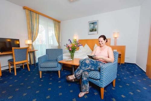 una mujer sentada en una mesa en una habitación de hotel en Gasthof Oberer Gesslbauer, en Stanz Im Murztal