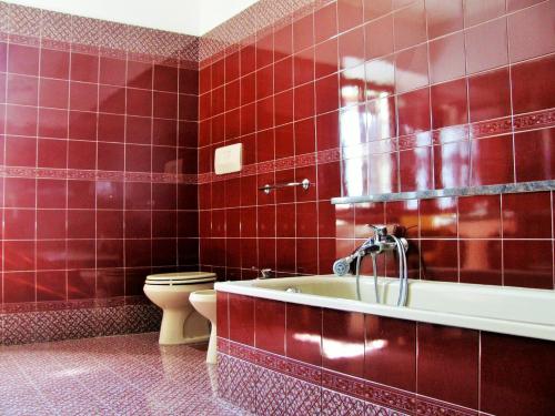 een rood betegelde badkamer met een bad en een toilet bij Alla casa del cedro in Cavedago