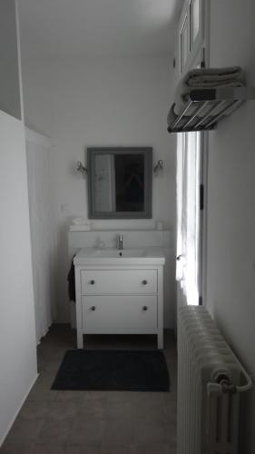 - une salle de bains blanche pourvue d'un lavabo et d'un radiateur dans l'établissement Chambre côté jardin, à Nîmes