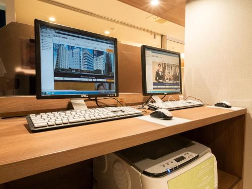 a desk with two computer monitors and a keyboard and mouse at Super Hotel Shinyokohama in Yokohama