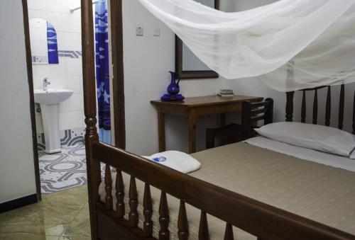 - une chambre avec un lit en bois, un lavabo et un lavabo dans l'établissement Entebbe Vine Inn, à Entebbe
