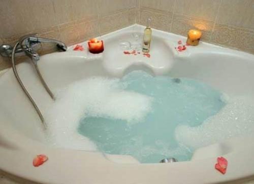 a bath tub filled with blue water and candles at Nof Kinneret Cabins in Had Nes