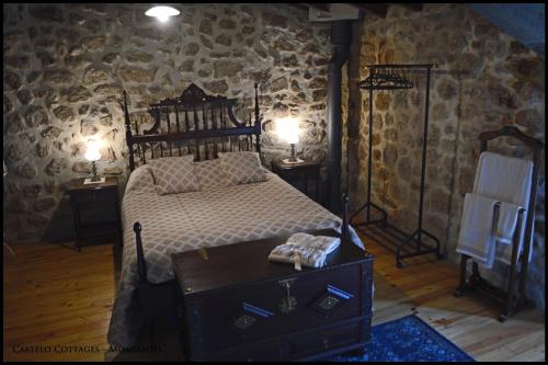 a bedroom with a bed in a stone wall at Castelo Cottages II in Monsanto