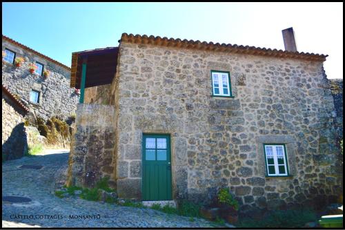 a stone building with a green door and windows at Castelo Cottages II in Monsanto