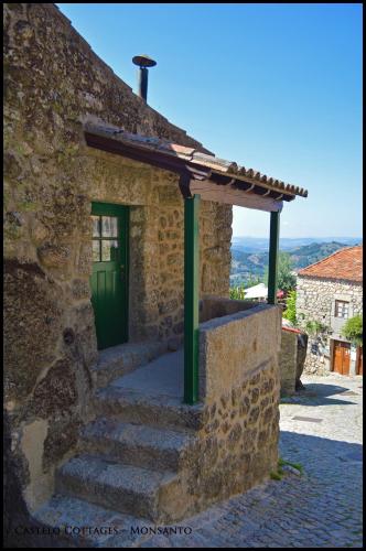 a stone building with a green door and stairs at Castelo Cottages II in Monsanto