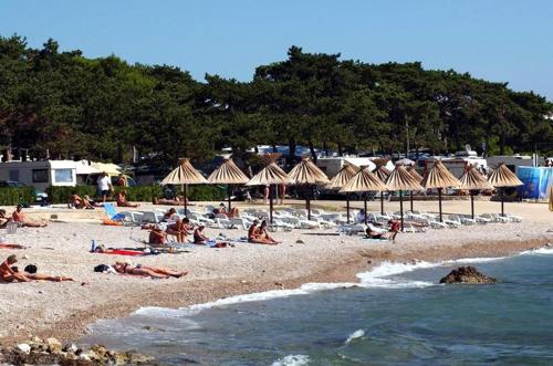 a group of people laying on a beach with umbrellas at Katy in Krk