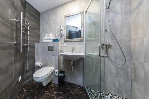 a bathroom with a shower and a toilet and a sink at Resort Hotel Elija in Šventoji