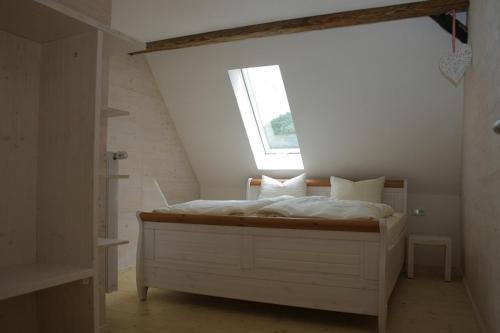 ein weißes Bett in einem Zimmer mit Fenster in der Unterkunft Mühlenchalet in Gundershofen
