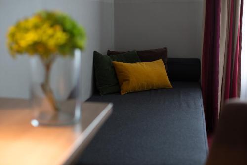 a couch with a yellow pillow and a vase of flowers at Hotel Wetterstein in Munich
