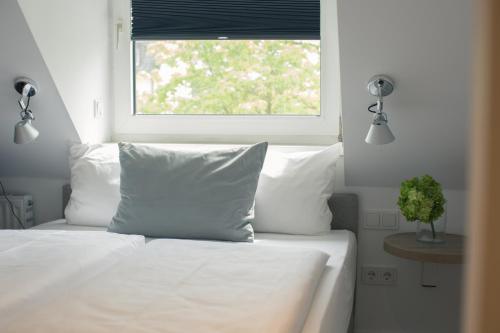 a bed with white sheets and pillows and a window at Hotel Wetterstein in Munich