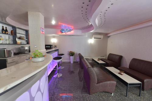 a waiting room with chairs and a bar with purple lighting at Hotel Perfect in Varna City
