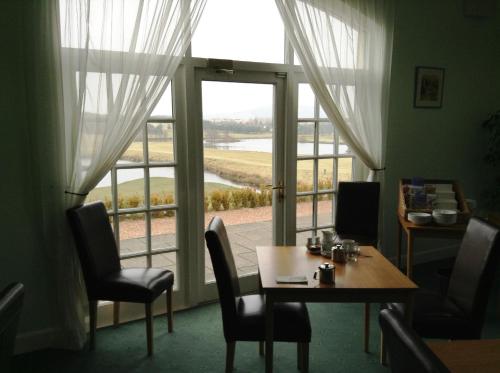 a dining room with a table and a large window at Drumoig Golf Hotel in St. Andrews
