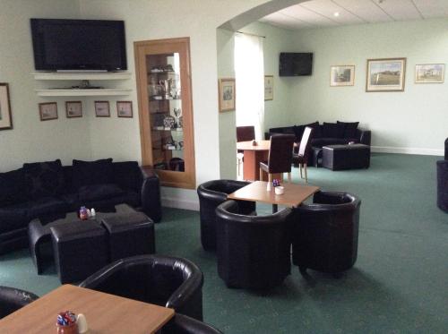 a waiting room with couches and tables and a tv at Drumoig Golf Hotel in St. Andrews