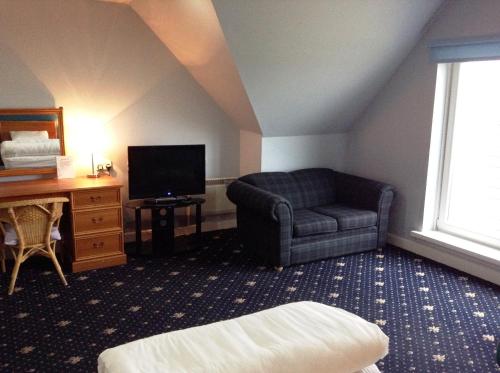 a living room with a chair and a television at Drumoig Golf Hotel in St. Andrews