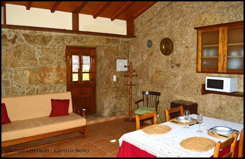 ein Wohnzimmer mit einem Tisch und einem Sofa in der Unterkunft Castelo Cottages in Castelo Novo