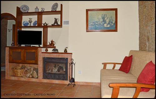 a living room with a fireplace and a tv at Castelo Cottages in Castelo Novo