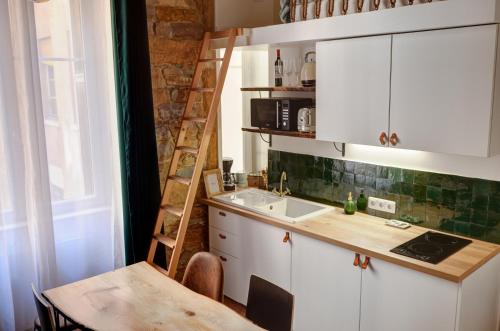 a kitchen with white cabinets and a sink and a ladder at La Casa Jungle Bed & Spa - Pentes de la Croix Rousse in Lyon