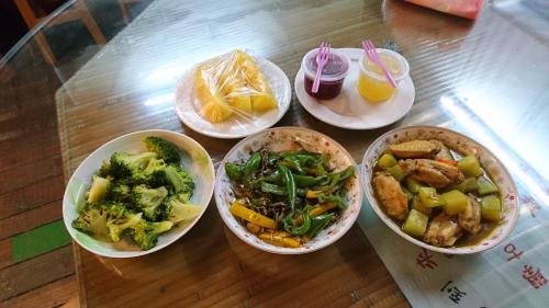 cuatro tazones de comida en una mesa de cristal en You Ye De Lin B&B en Meishan