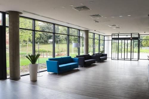 a lobby with blue couches and windows in a building at Várda Sport Hotel in Kisvárda