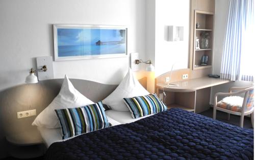 ein Schlafzimmer mit einem Bett mit zwei Kissen und einem Schreibtisch in der Unterkunft MediTerra in Papenburg