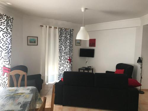 a living room with a black couch and a tv at Hospedaria A Primorosa in Nazaré