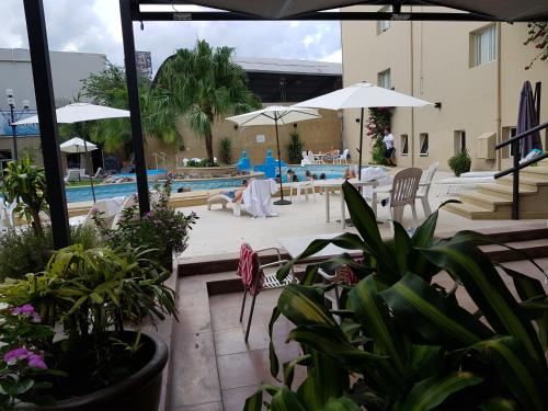 una piscina con mesas, sillas, sombrillas y plantas en Hotel Termal Rio Hondo en Termas de Río Hondo