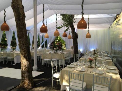 a white tent with white tables and chairs and lights at El Rincon Eco Hotel in Los Ángeles