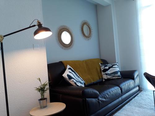 a black leather couch in a living room with a lamp at Chalet du Doumet - Appart LUZ centre - parking et garage individuel ferme - draps et serviettes inclus in Luz-Saint-Sauveur