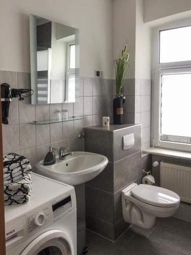 a bathroom with a sink toilet and a washing machine at Ferienwohnung am Schlossparkcenter in Schwerin