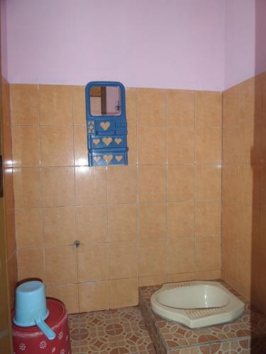 a bathroom with a toilet in a tiled wall at Pondok Stevia Ciwidey in Ciwidey