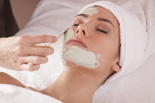 a woman in a towel brushing her face with a spoon at Hotel Del Buono Wellness & Medical Spa in Chianciano Terme