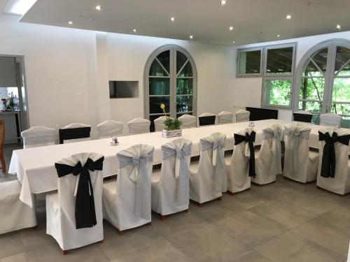 a room with a long table with white tables and chairs at Rómahegy Rendezvényház in Kaposvár