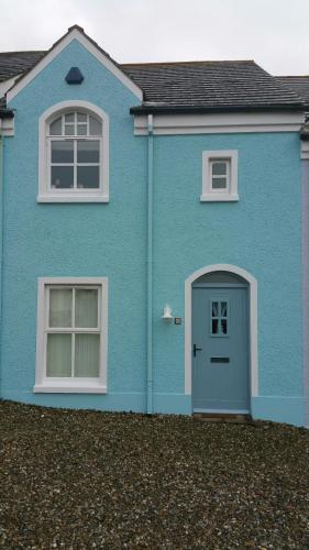 a blue house with a door and two windows at Beech House in Portballintrae