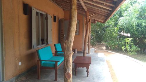2 Stühle und ein Tisch auf der Veranda eines Hauses in der Unterkunft Taragala Chalets in Kalametiya
