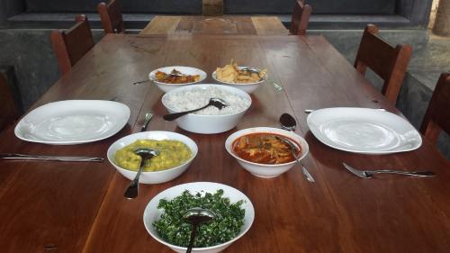 a wooden table with bowls and plates of food on it at Taragala Chalets in Kalametiya