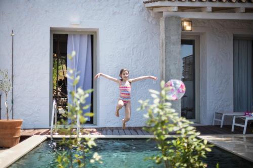 Ein junges Mädchen springt in ein Schwimmbad in der Unterkunft Villa Vivere in Asos