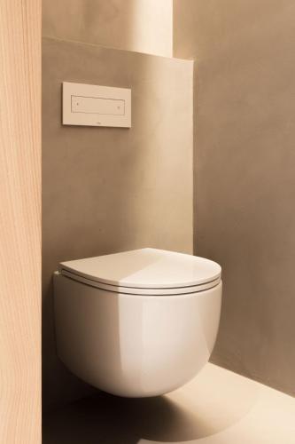 a white toilet in a bathroom with a lightswitch at Schgaguler Hotel in Castelrotto