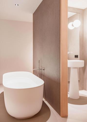 a bathroom with a white tub next to a sink at Schgaguler Hotel in Castelrotto