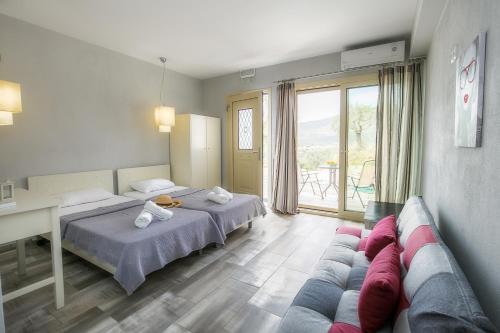 リメナリアにあるThea Athosのベッド2台とソファが備わるホテルルームです。