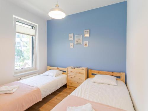 two beds in a room with a blue wall at Rezydencja Ustronie Morskie 5/5 in Ustronie Morskie