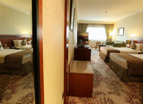 a hotel room with three beds and a living room at Ramee Royal Hotel in Dubai