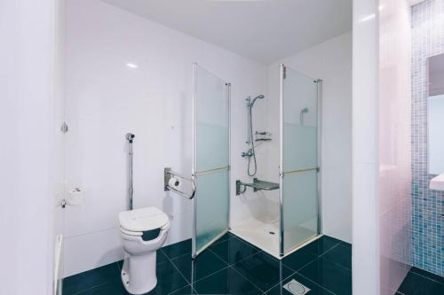 a bathroom with a toilet and a glass shower at Muthu Raga Madeira Hotel in Funchal