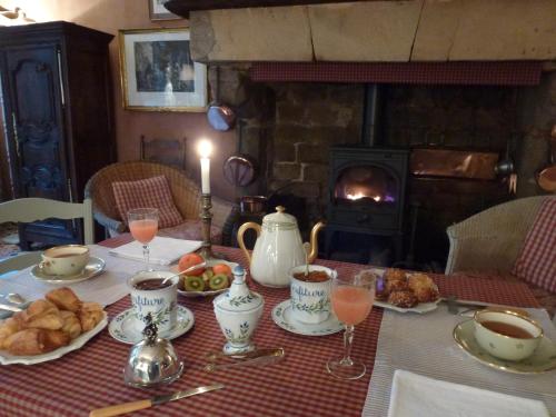 einen Tisch mit Speisen und Getränken und einen Kamin in der Unterkunft Hôtel Tanquerey de La Rochaisière in Coutances