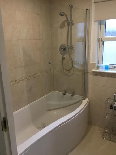 a white bath tub with a shower in a bathroom at Inchmarlo villa27 in Banchory