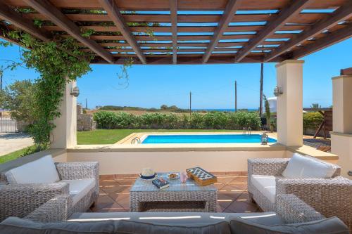 a patio with chairs and a table and a swimming pool at Villa Lahania in Lachania