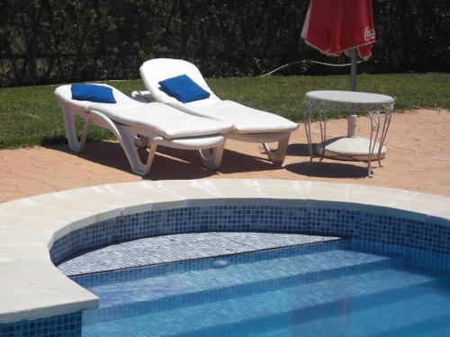 two chairs and a table next to a swimming pool at Finca Esmeralda in Zahora