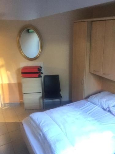 a bedroom with a bed and a chair and a mirror at Prinses Elisabeth in Koksijde