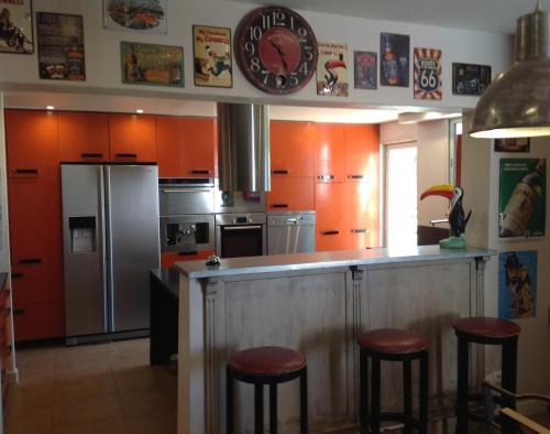 a kitchen with orange cabinets and a counter with bar stools at La Bonne Mine in Le Fraysse